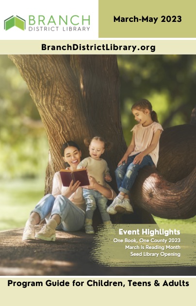 Woman reading to two children in front of a tree in Spring weather. 