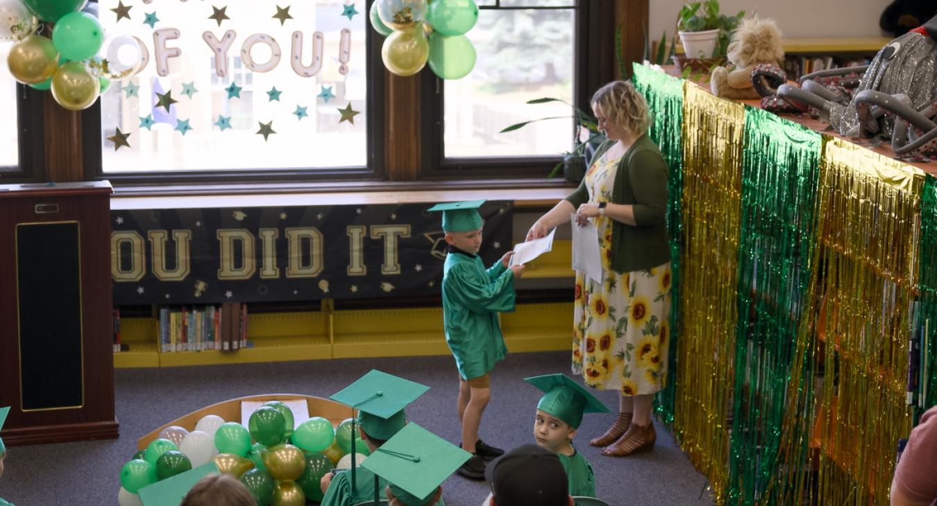 boy recieveing a paper certificate from a library staff member 