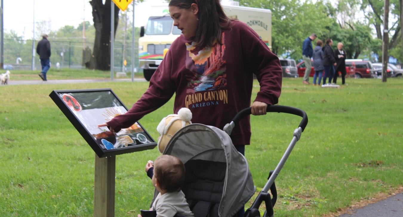 family with stoller reads the storywalk sign at waterworks park in coldwater